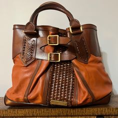 This Pre-Owned Burberry Bridle 2way Woven Accents Bag Is Guaranteed 100% Authentic, In Good Condition The Exterior Is Free Of Any Rips Or Cracks, There Are Very Few Scuffs And Scratches Throughout. The Corners And Pipping Are In Excellent Used Condition. The Leather Handles Show Minor Wear. The Zipper And Magnetic Closures Operate Properly And Runs Smoothly. The Hardware Shows Light Wear. The Interior Has No Stains And Features Two Magnetic Closure Sections And Multiple Zipper Pockets For Plenty Of Storage. Burberry Purse, Leather Handles, 2 Way, Burberry Bag, Magnetic Closure, Leather Handle, Accent Colors, Zipper Pocket, Burberry