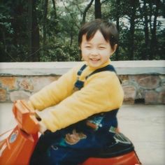 a young boy riding on the back of a red motorcycle