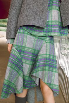 a woman in grey jacket and green plaid skirt