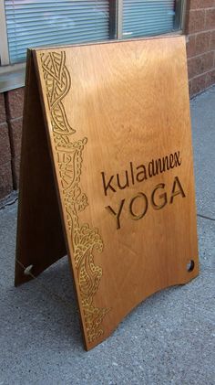 a wooden sign that says kulamnex yoga on the side of a building