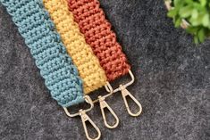 there are three crocheted scissors on the table next to each other and one is holding two hooks