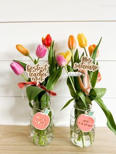 two vases filled with flowers on top of a wooden table next to each other