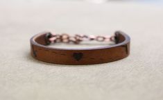 a brown leather bracelet with a heart on it