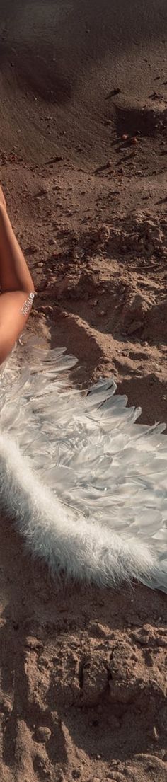 a woman laying on the beach with her arms behind her head and legs in the water