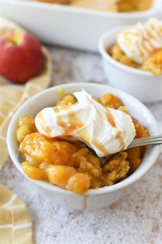 a bowl filled with fruit and topped with whipped cream next to another bowl full of apples