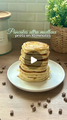 a stack of pancakes sitting on top of a white plate next to a potted plant