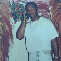 a man standing in front of a wall talking on a cell phone with his hand up to his ear