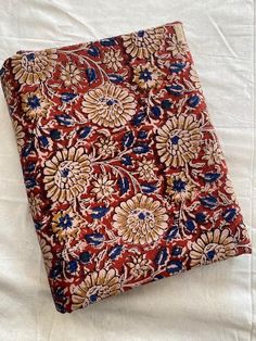 a red and blue flowered cloth laying on top of a white sheet