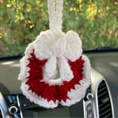 a red and white crocheted ornament hanging from the dashboard of a car