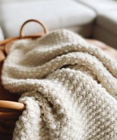 a white blanket sitting on top of a wooden basket