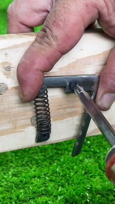 a person holding a pair of scissors over a piece of wood