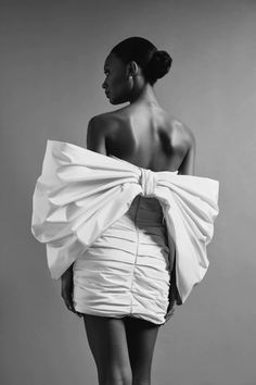 a woman in a short white dress is standing with her back turned to the camera