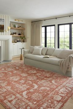 a living room filled with furniture and a large rug on top of a hard wood floor