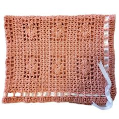 an orange crocheted blanket with white ribbon