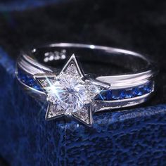 a white gold ring with blue sapphires in the center and a star shaped diamond on top