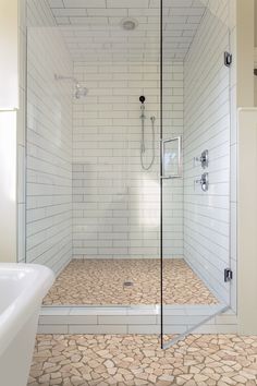 a walk in shower sitting next to a white bath tub