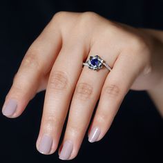 a woman's hand with a ring on it and a blue stone in the middle