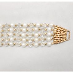 This is part of Chairish’s Costume Jewelry assortment.  1950s goldtone 5-strand round faux-moonstone beads and faceted clear glass beads with small round goldtone bead spacers bracelet with fold over clasp. Marked "Napier." Measures: 8 inches long 1 9/16 inches across. Condition: Good; a bit of scratching and wear to the clap and the where it connects to the bracelet, with some wear to the small goldtone spacer beads. The matching necklace and clip earrings are also available. Formal Vintage Beaded Bracelets With Round Beads, Vintage Gold Bracelets With Faceted Beads, Vintage Faceted Beads Bracelet, Vintage Gold Beaded Bracelets With Faceted Beads, Vintage Gold Beaded Bracelet With Spacer Beads, Vintage Gold Pearl Bracelet With Round Beads, Gold Vintage Pearl Beaded Bracelet, Formal Beaded Bracelets, Formal Beaded Crystal Bracelet With Round Beads