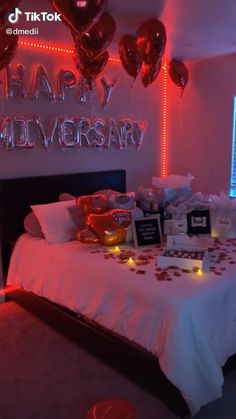 a bed in a room with balloons and gifts on the table next to it that says happy anniversary