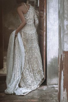 a woman in a white dress is standing by a door and looking at the floor