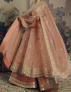 a woman in a pink lehenga with gold embroidery on the sleeves and bottom