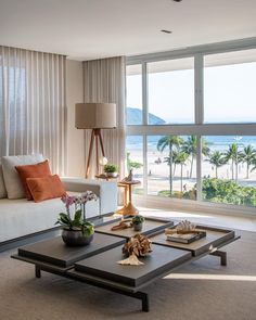 a living room filled with furniture and a large window overlooking the beach in front of it