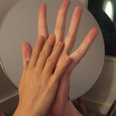 two hands reaching up to each other in front of a round table with a mirror behind it