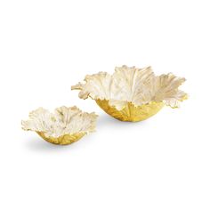 two gold leaf shaped dishes on a white background