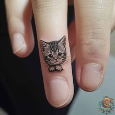 a small cat tattoo on the finger