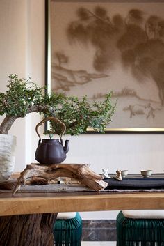 a potted plant sitting on top of a wooden table in front of a painting