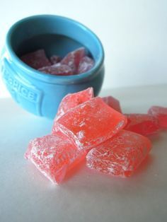 some gummy bears are sitting next to a blue bowl full of sugar cubes