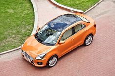 an orange car driving down a street next to grass