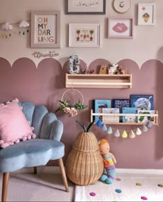 a living room with pink walls and blue chairs in front of the wall has pictures on it