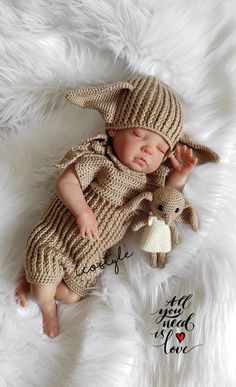 a baby wearing a knitted hat and holding a stuffed animal is laying on a fluffy white blanket