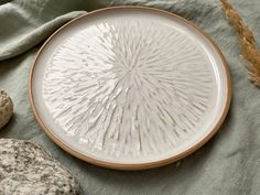 a white plate sitting on top of a table next to some rocks and a plant