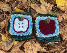 two crocheted apples are laying on the ground with leaves around them and one has an apple in it