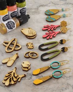 wooden earrings and other crafting supplies on a marble counter top with markers, glues, and ink