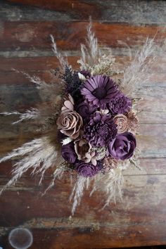 a bridal bouquet with purple flowers and feathers