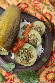 an eggplant stuffed with meat and rice on a plate next to a pickle