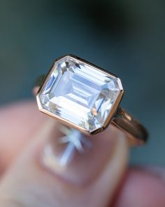 a close up of a person's hand holding an engagement ring