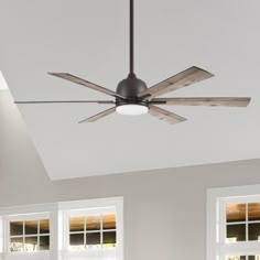 a ceiling fan mounted to the side of a wall in a room with two windows