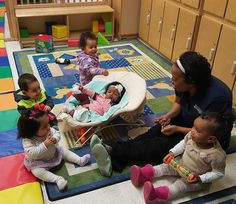 a group of children sitting on the floor in a play room with their moms