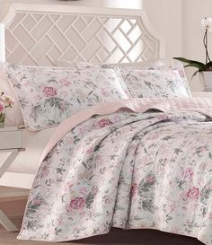 a white bed with pink flowers on it and a flowered comforter in the background