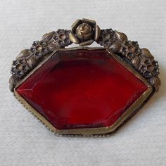 For your consideration we have a lovely lapel pin/brooch from the Victorian era. This pin is stunning in detail and color, done with bright red glass stone and bordered on the top by a floral design of brass. We believe this pin was upcylced from a possible shoe buckle. Measuring approximately 1.5" long and 1.25" tall, this is a great accessory for any dapper gent or well turned out woman.Shipping policies:If you choose to pay via Paypal, you must either be a verified buyer, or provide a confirm Vintage Red Lapel Pin For Gift, Red Vintage Lapel Pin For Gift, Vintage Red Lapel Pin As Gift, Red Vintage Lapel Pin As Gift, Antique Red Brooch Jewelry, Antique Red Brooch, Antique Red Brooch For Formal Occasions, Vintage Red Brooches For Formal Occasions, Antique Red Brooch As Gift