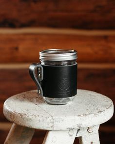 a mason jar sitting on top of a stool with a black leather cover over it