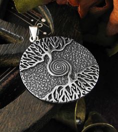 Material: 100% Sterling silver Weight: 6.4 grams Size: Almost 1-1/8 inch diameter (28 mm) Item number: wh286 With a spiral symbol interwoven into its design, this dramatic pendant adds new meaning to the adage 'As Above So Below'. The trunk that supports the upper half of the tree joins with the trunk rising from the tree's roots, each curling itself into alternating layers of the spiral. The finally join together as a single point at the spiral's center. The crown (or top) of the tree and its c Spiral Sterling Silver Jewelry With Oxidized Finish, Spiral-shaped Engraved Sterling Silver Jewelry, Engraved Sterling Silver Spiral Jewelry, Symbolic Spiral Sterling Silver Jewelry, Spiritual Silver Jewelry With Artistic Design, Silver Spiritual Jewelry With Artistic Design, Unique Silver Spiral Necklace, Silver Jewelry With Artistic Design In Round Pendant, Silver Jewelry With Artistic Design Round Pendant