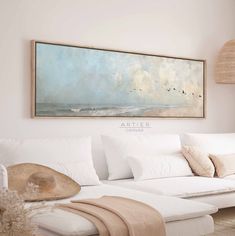 a living room with white furniture and a painting on the wall above it's couch