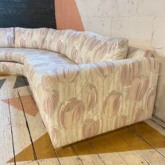 a curved couch sitting on top of a wooden floor