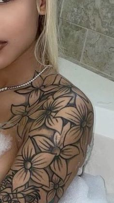 a woman with tattoos on her chest in a bathtub