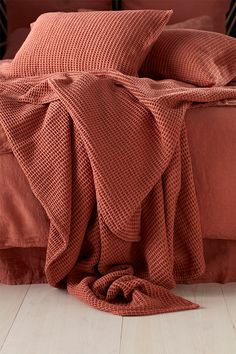 a bed covered in an orange blanket and pillows